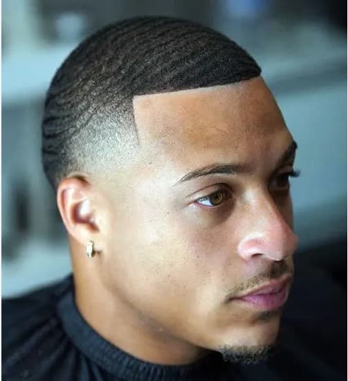 A man with 360 waves, a sharp line-up, and a clean skin fade haircut.