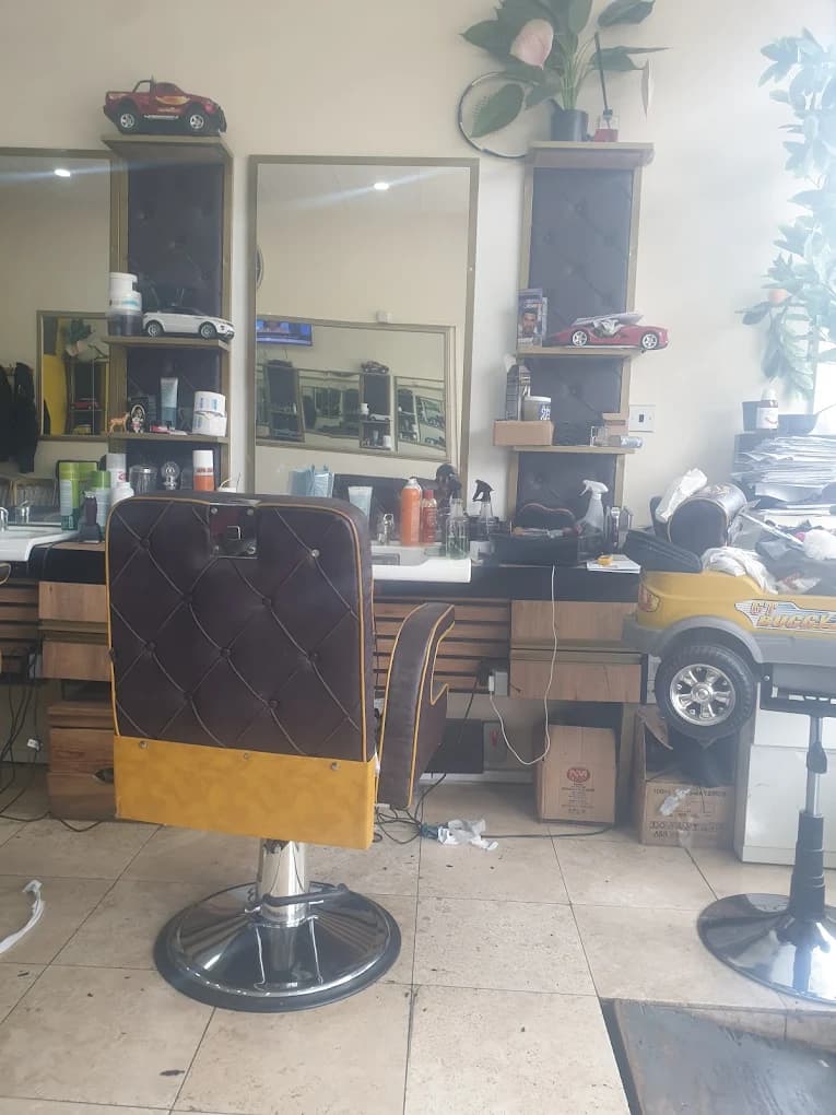Barber shop interior with a brown tufted chair and a yellow toy car seat.