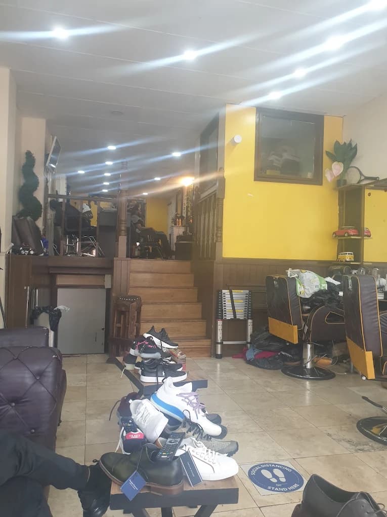Barbershop interior with shoes on a foreground table and stairs leading to an upper level.