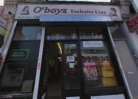 O'boyz Exclusive Cutz barbershop storefront with posters in the windows and an open entrance.