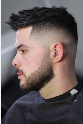 Profile of a man with a textured high skin fade haircut and sharp groomed beard.