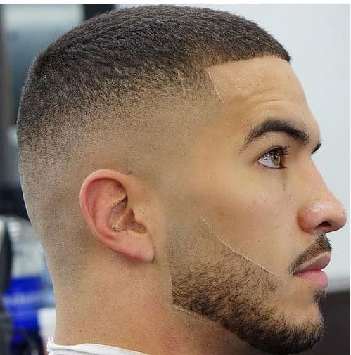 Man with a buzz cut, high skin fade, and a precisely shaped short beard.
