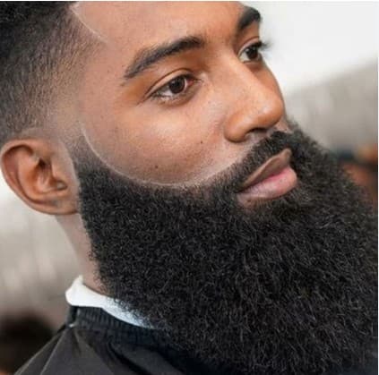 A Black man with a thick, groomed beard and a sharp, clean fade haircut.