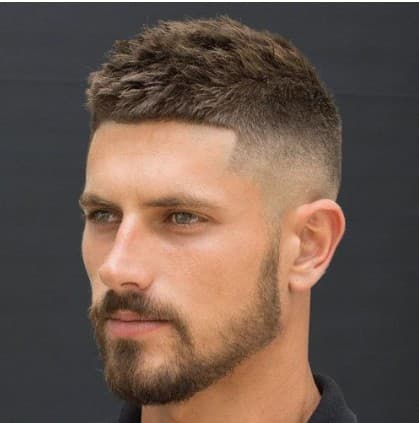 Man with a short textured haircut, high skin fade, and a neatly groomed short beard.