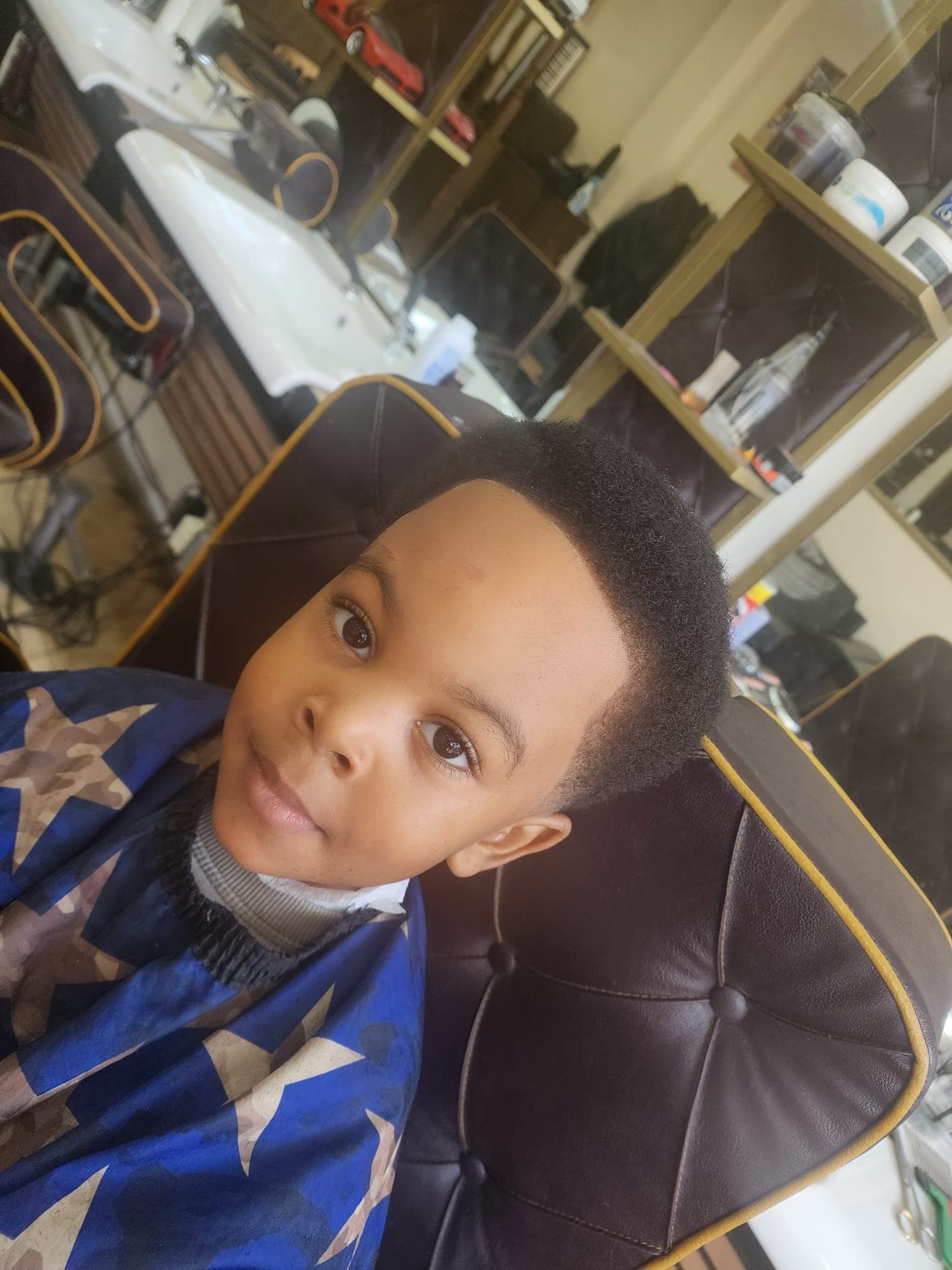 Young boy with a fresh haircut and clean hairline sitting in a leather barber chair.