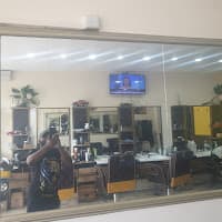 Mirror reflection of a barbershop interior with a person taking a selfie and barber chairs.