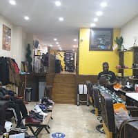 Barber cutting a customer's hair in a brightly lit barbershop with yellow walls and stairs.